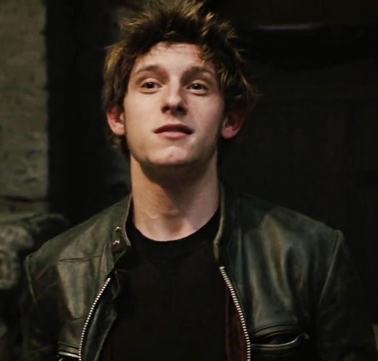 a young man wearing a black shirt and leather jacket