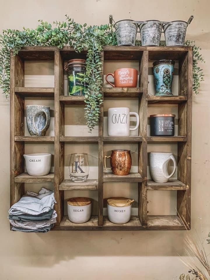 an old wooden shelf filled with dishes and mugs next to a wall mounted potted plant