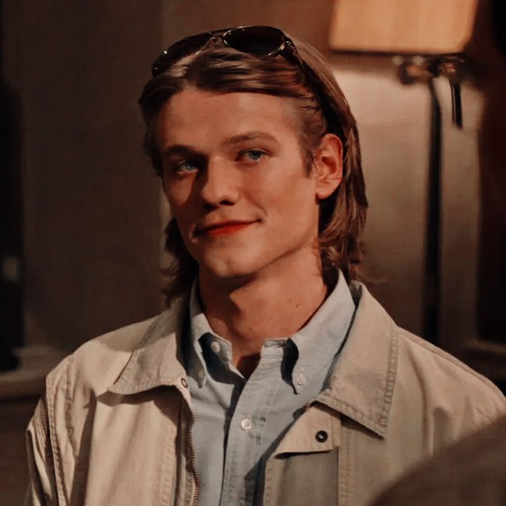 a young man with sunglasses on his head looking at the camera while standing in front of a lamp