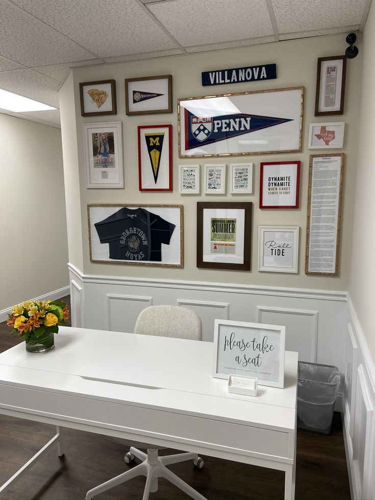 a white desk sitting in front of a wall with pictures on it