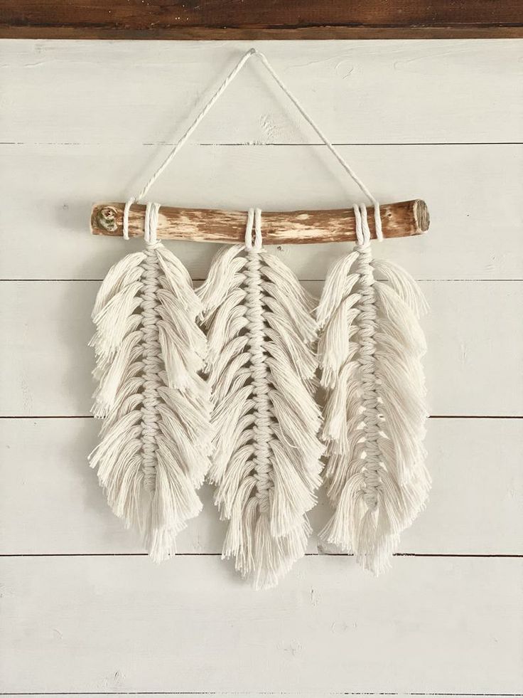 three white feathers hanging on a wall