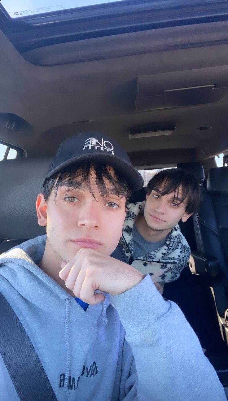 two young men sitting in the back seat of a car