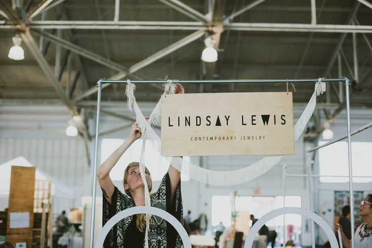 a woman holding up a sign in front of a computer screen with the words lindsey lewis on it