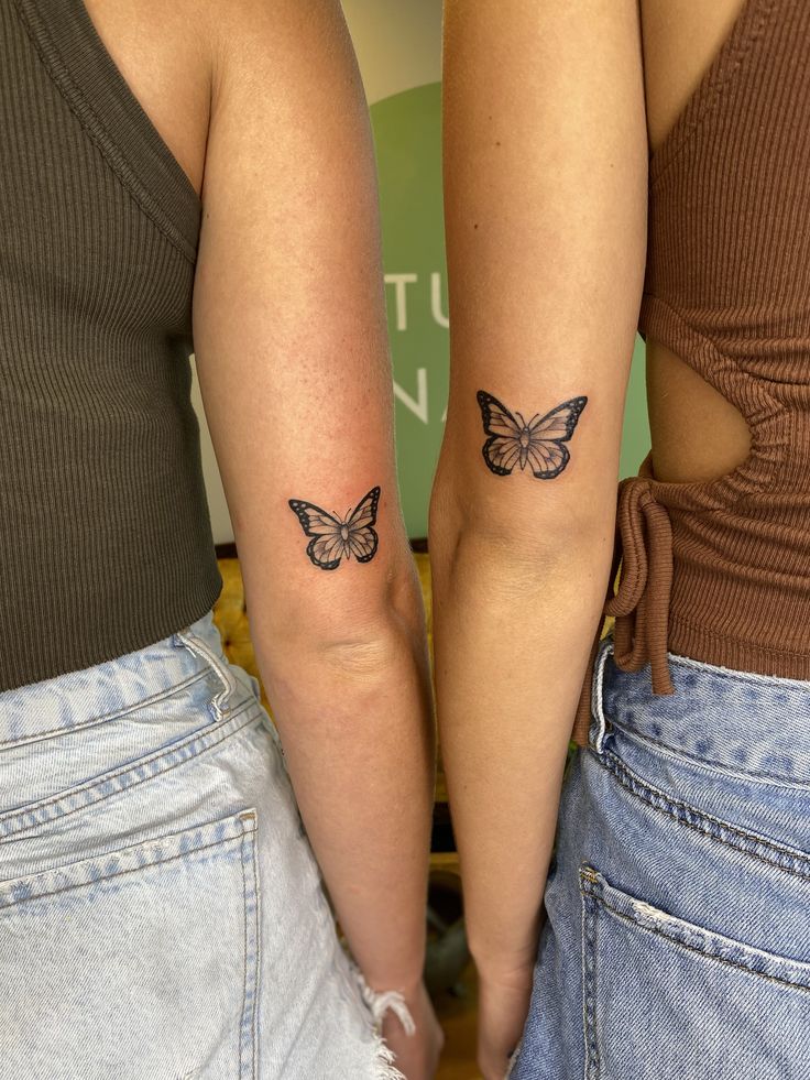 two women with matching butterfly tattoos on their arms