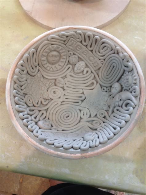 a white bowl sitting on top of a table next to a plate with an intricate design