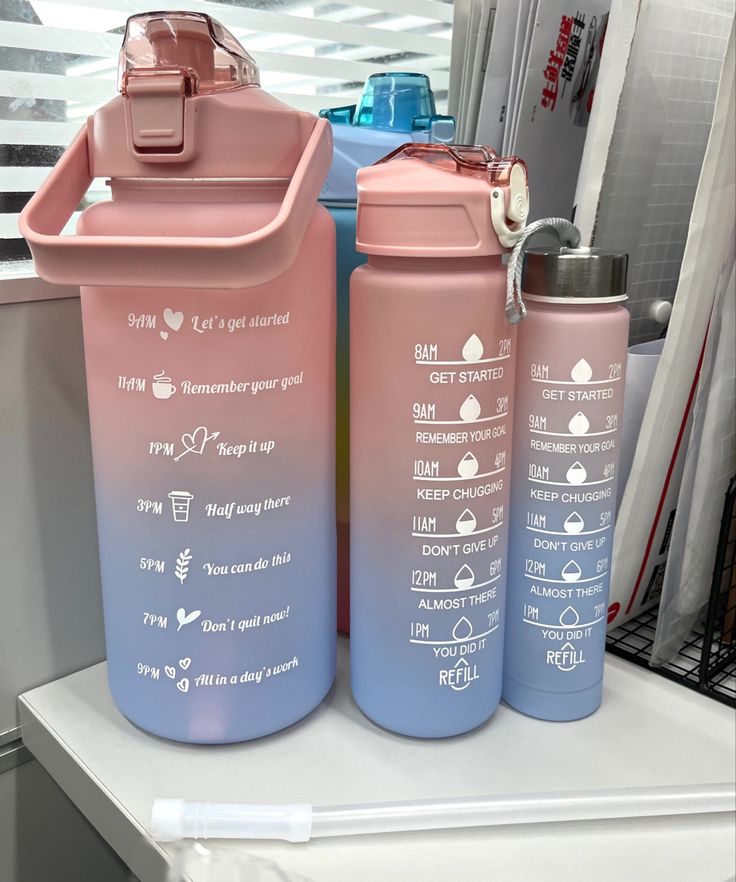 two pink and blue water bottles sitting next to each other on top of a counter