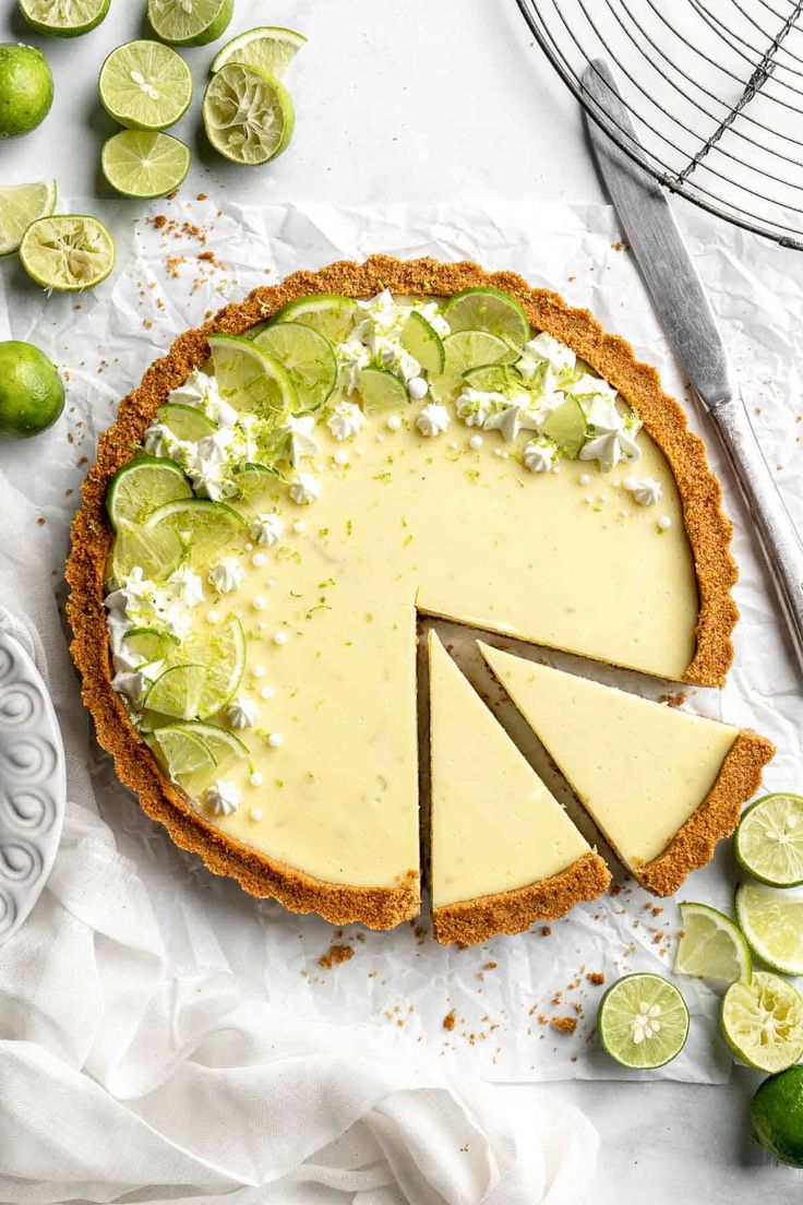 a cheesecake with limes and whipped cream on top, surrounded by lime slices