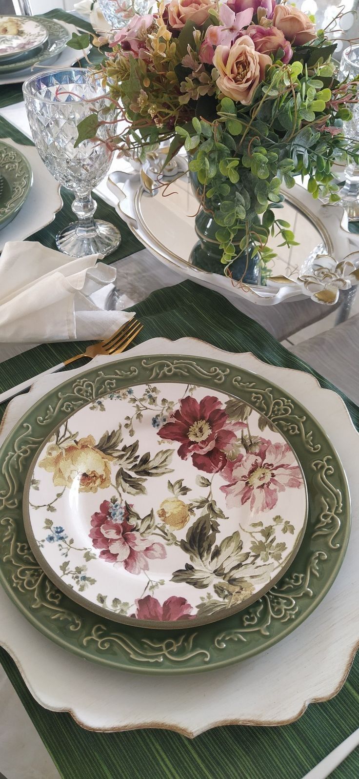 the table is set with plates, silverware and flowers in vases on it