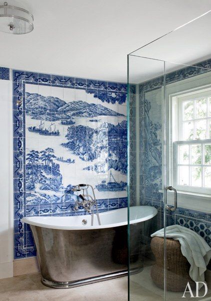 a bathroom with blue and white tiles on the walls, an old bathtub in the middle