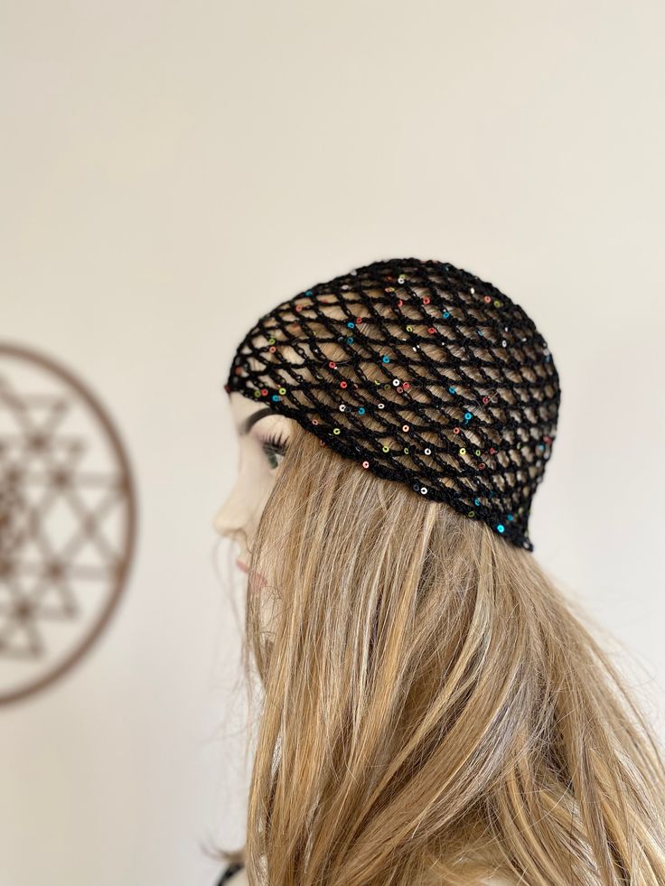 a woman with long hair wearing a black knitted headband and standing in front of a white wall