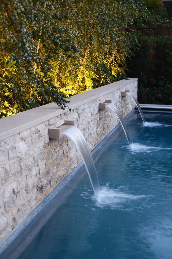 an outdoor swimming pool with water spouting from the side