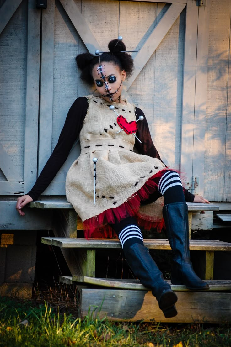 a woman dressed up as a clown is sitting on a wooden bench in front of a barn