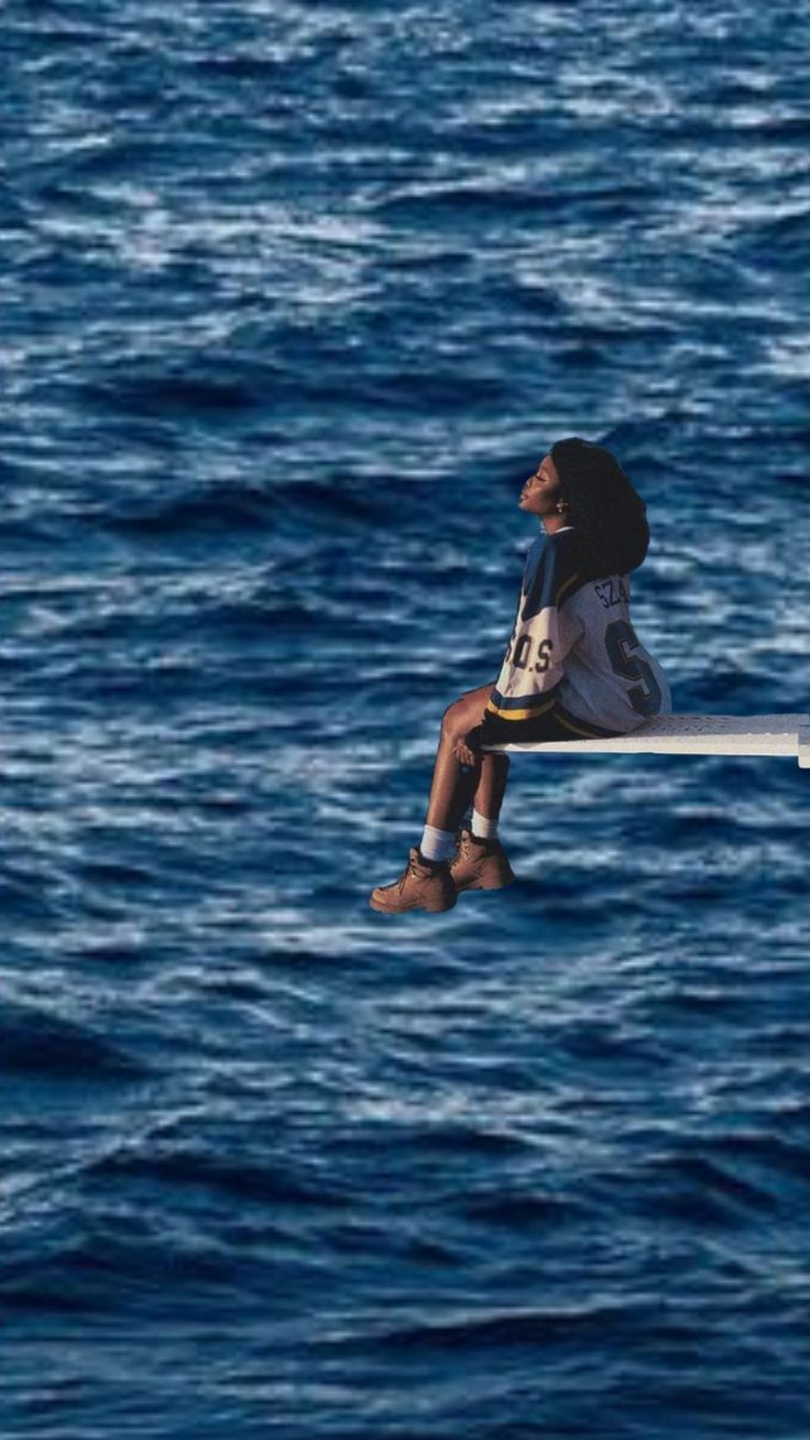 a man is sitting on a boat in the middle of the ocean with his head above the water