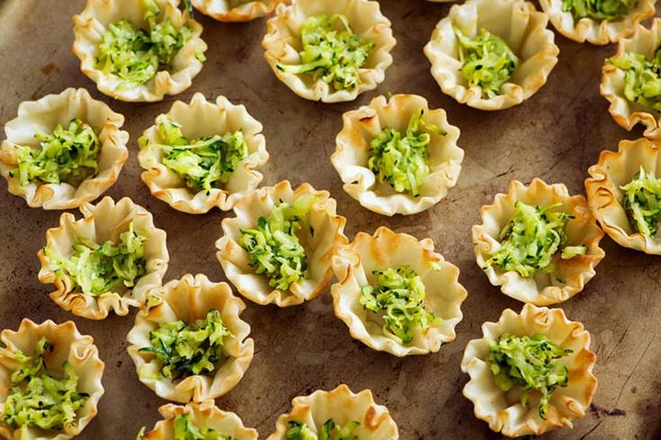 small appetizers with broccoli in them on a wooden tray, ready to be eaten