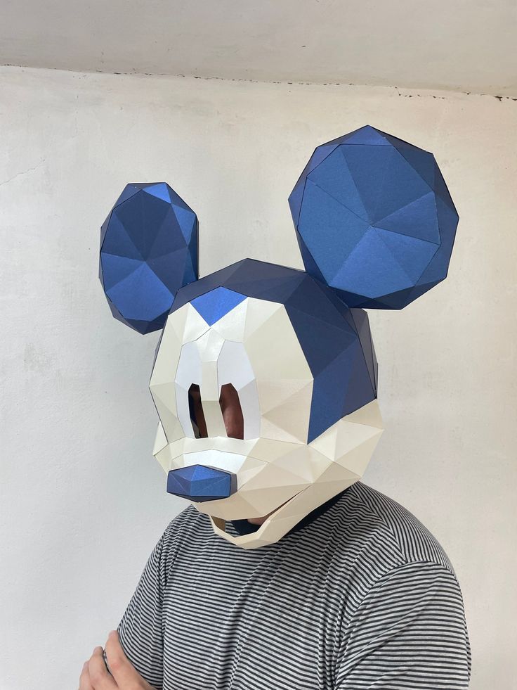 a man wearing a mickey mouse mask made out of blue and white geometric polygonics