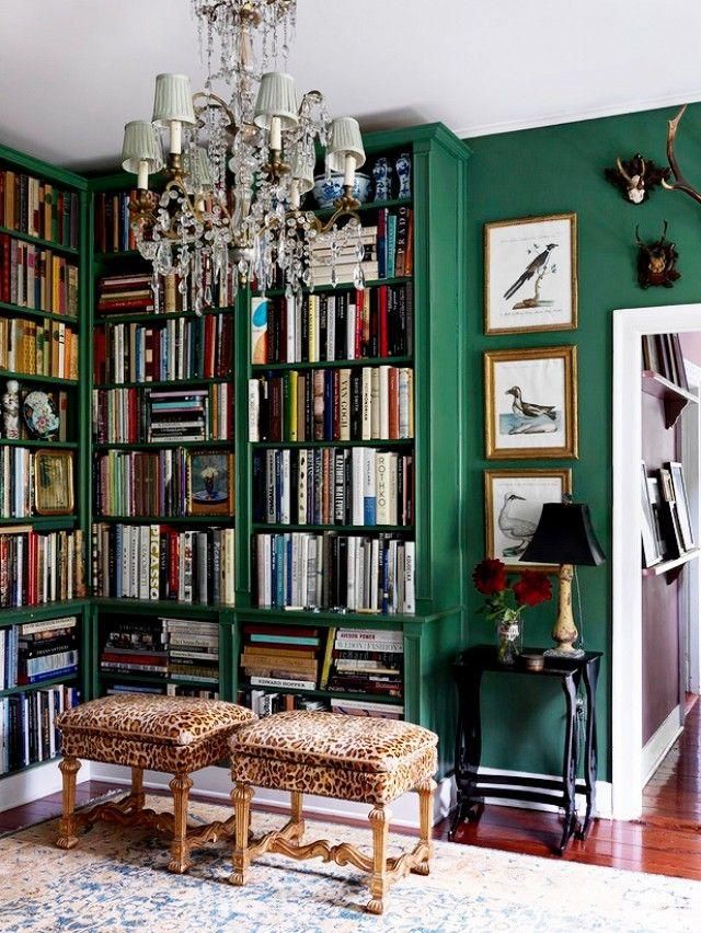 a living room filled with lots of books and a chandelier hanging from the ceiling