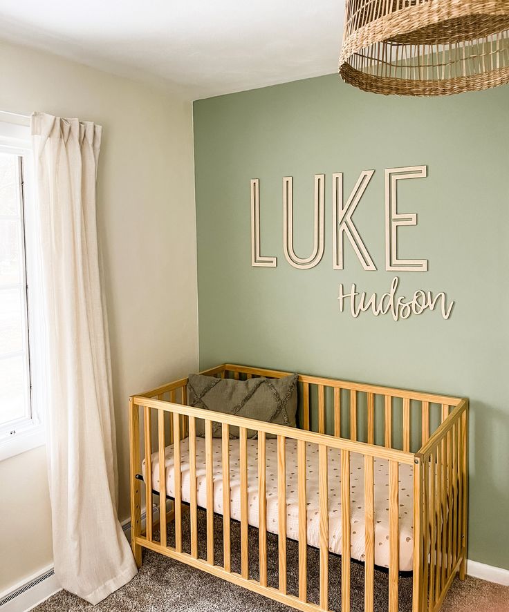 a baby's room with a wooden crib in the corner and a name on the wall