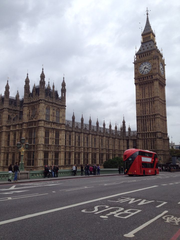 the big ben clock tower towering over the city of london as people walk across the street