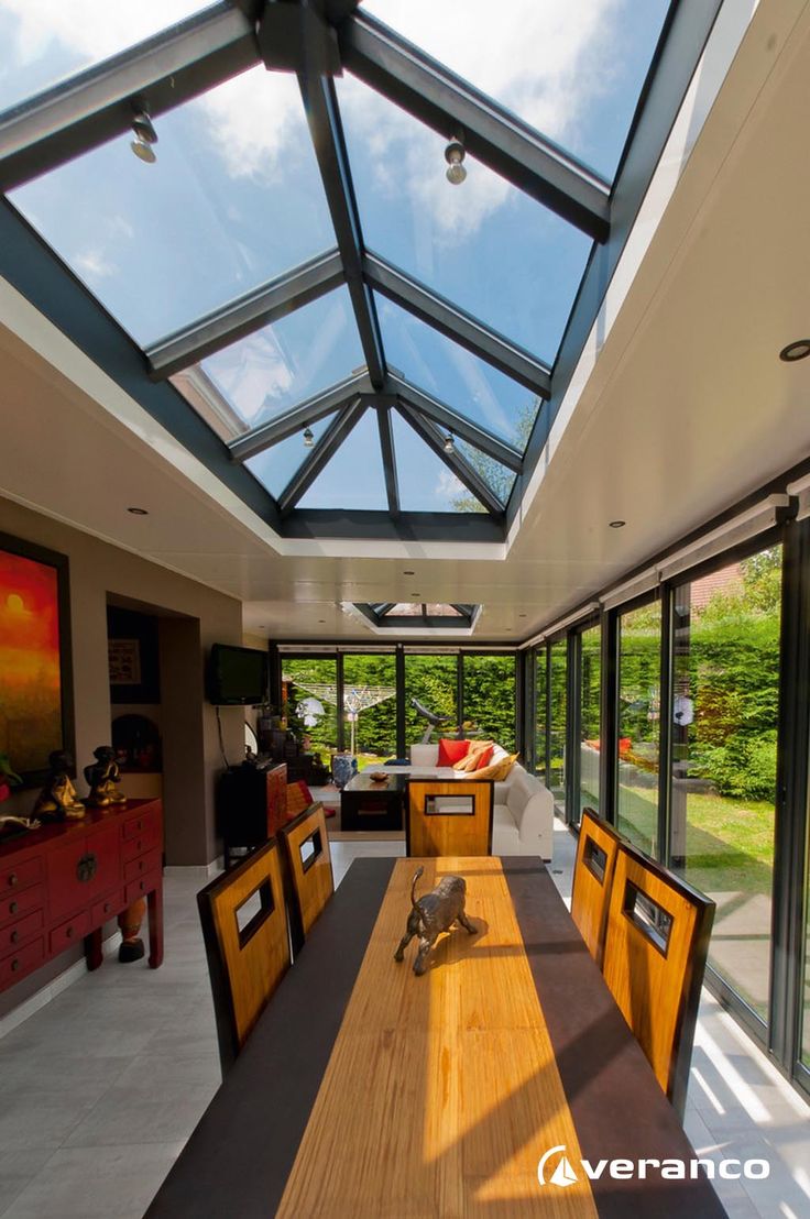 a large wooden table sitting under a skylight in a room with lots of windows