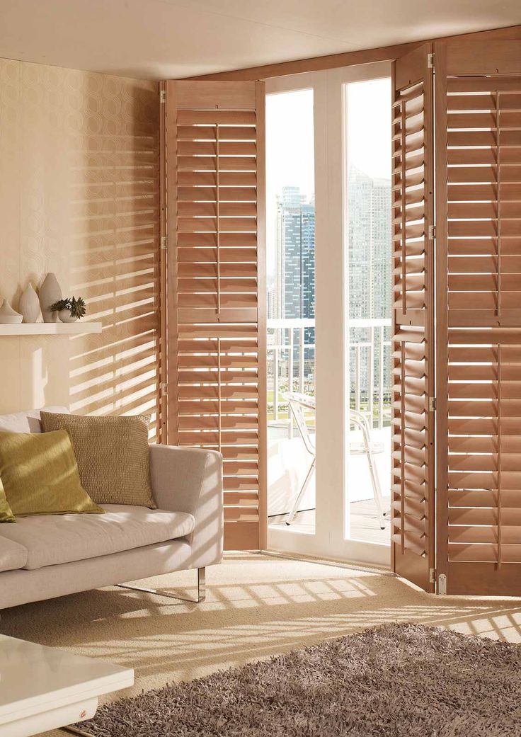 a living room with wooden shutters and a couch in front of the sliding glass door