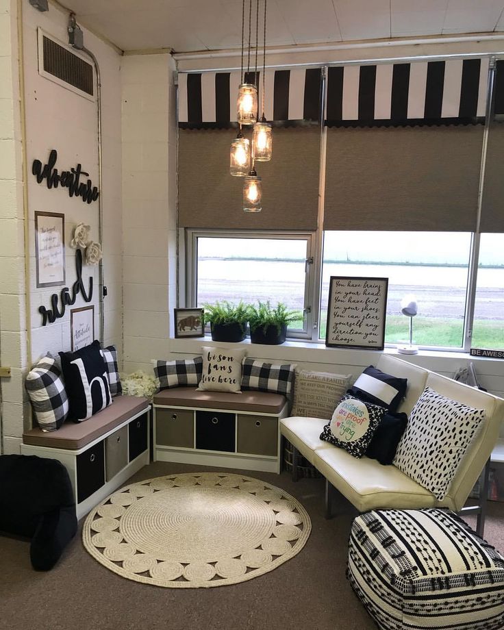 a living room filled with lots of furniture next to a window covered in black and white pillows