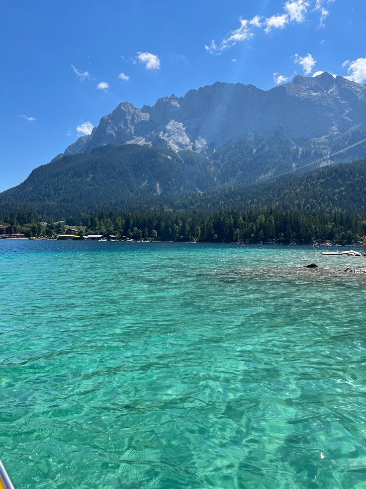 the water is crystal blue and clear with mountains in the background, as seen from a boat