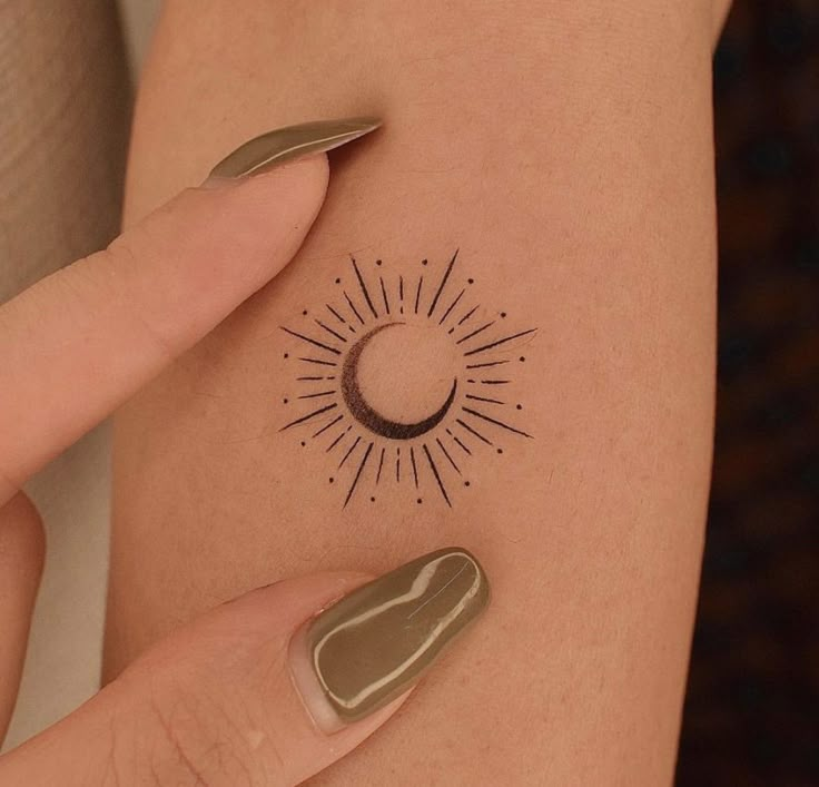 a woman's arm with a sun and moon tattoo on the left side of her body