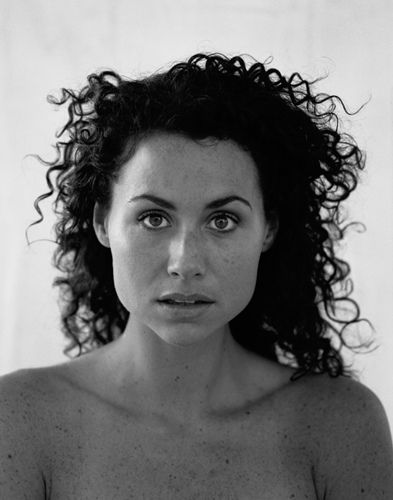 a black and white photo of a woman with frizz on her hair looking at the camera