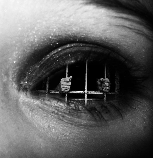 a person's eye with jail bars in the middle of their iris and hands on top of them