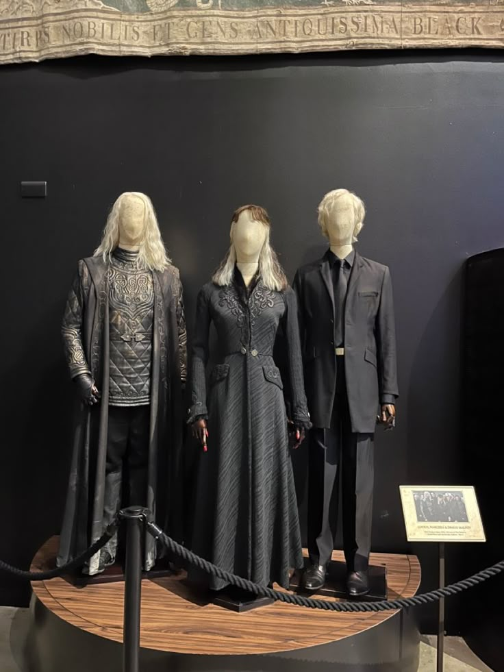 three mannequins dressed in black and white clothing on display at a museum