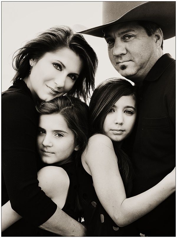 a black and white photo of four people posing for a group shot with one woman wearing a cowboy hat