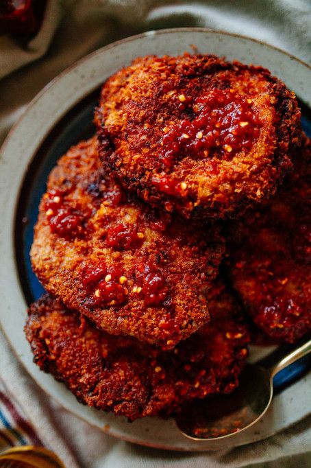 three fried meat patties on a blue plate with a spoon and napkin next to them