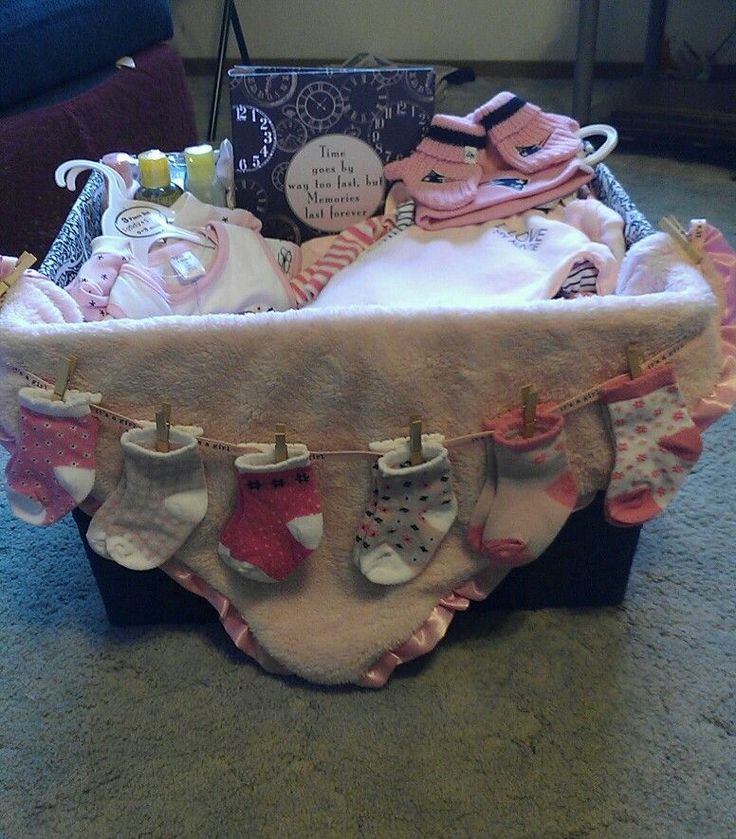 a basket filled with baby's clothes and socks on the floor next to a book