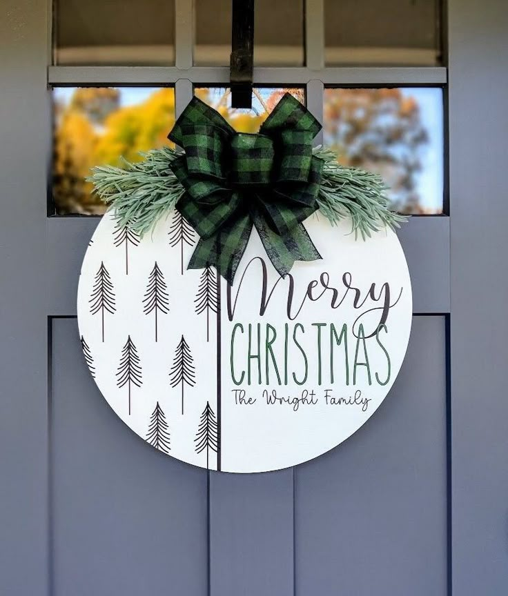 a merry christmas sign hanging on the side of a door with pine trees and evergreens