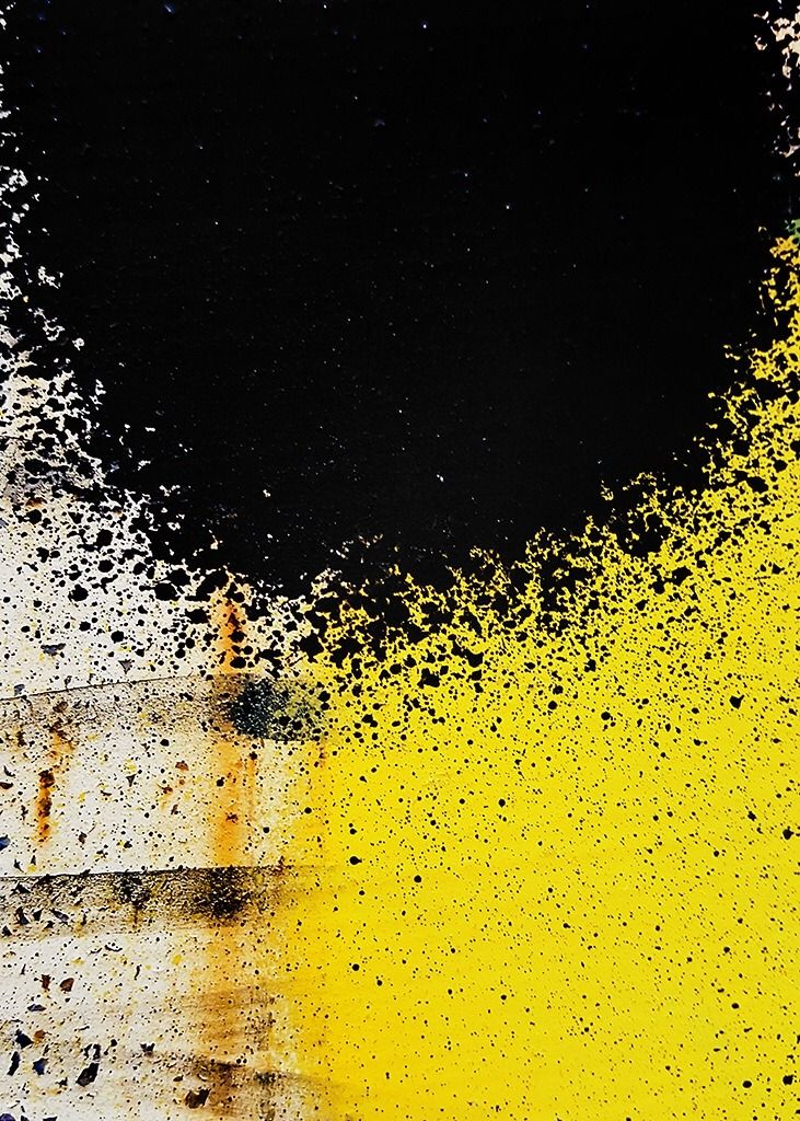 yellow and black paint splattered on the side of a white building with a dark sky in the background