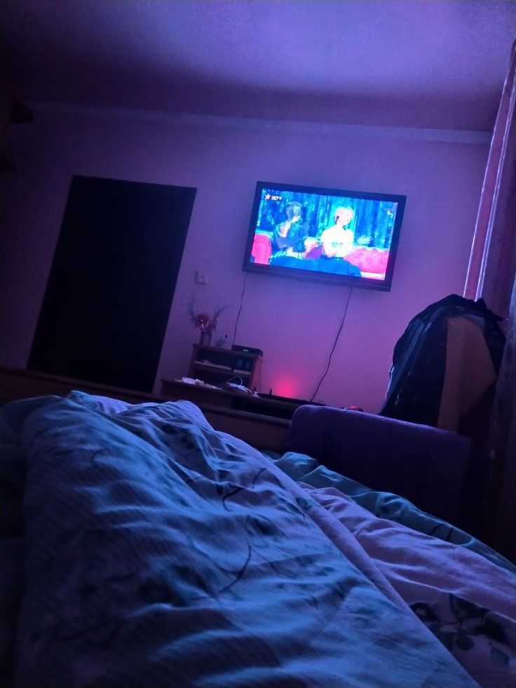 the television is on in the room with no one around it and there is also a bed