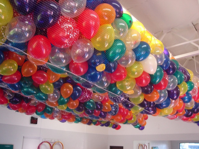 a room filled with lots of colorful balloons hanging from the ceiling and on top of each other