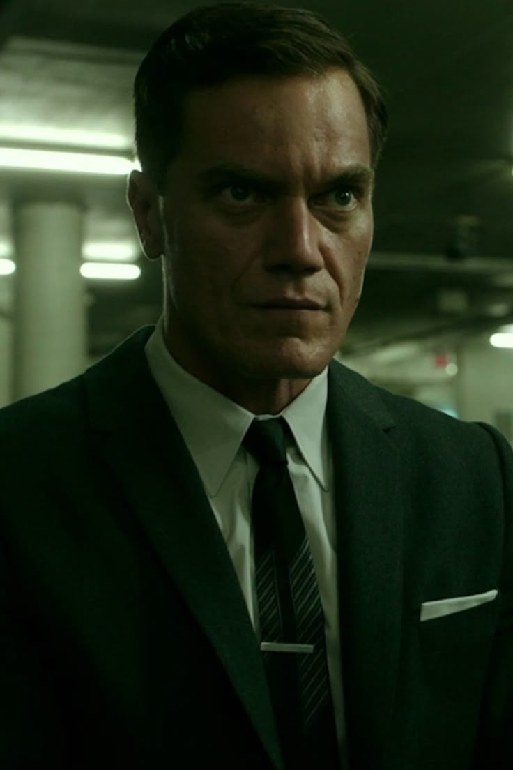 a man in a suit and tie looking at the camera with serious look on his face