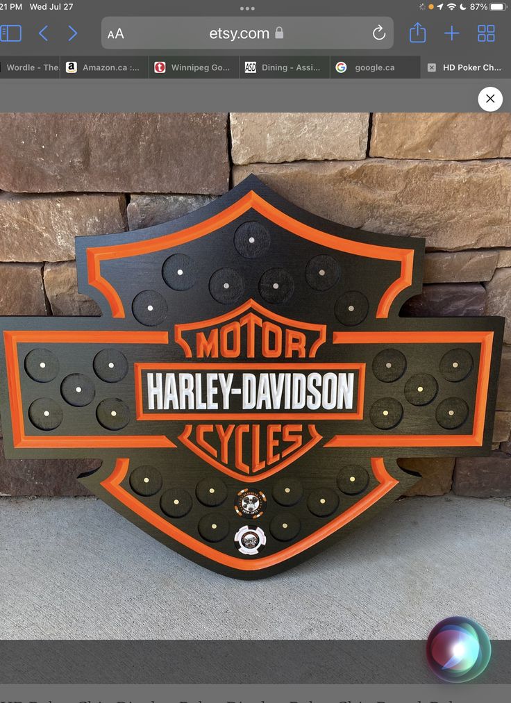 the harley davidson logo is on display in front of a stone wall and brick wall