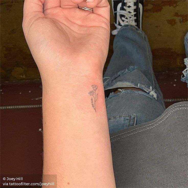 a woman's arm with a small flower tattoo on the left side of her wrist