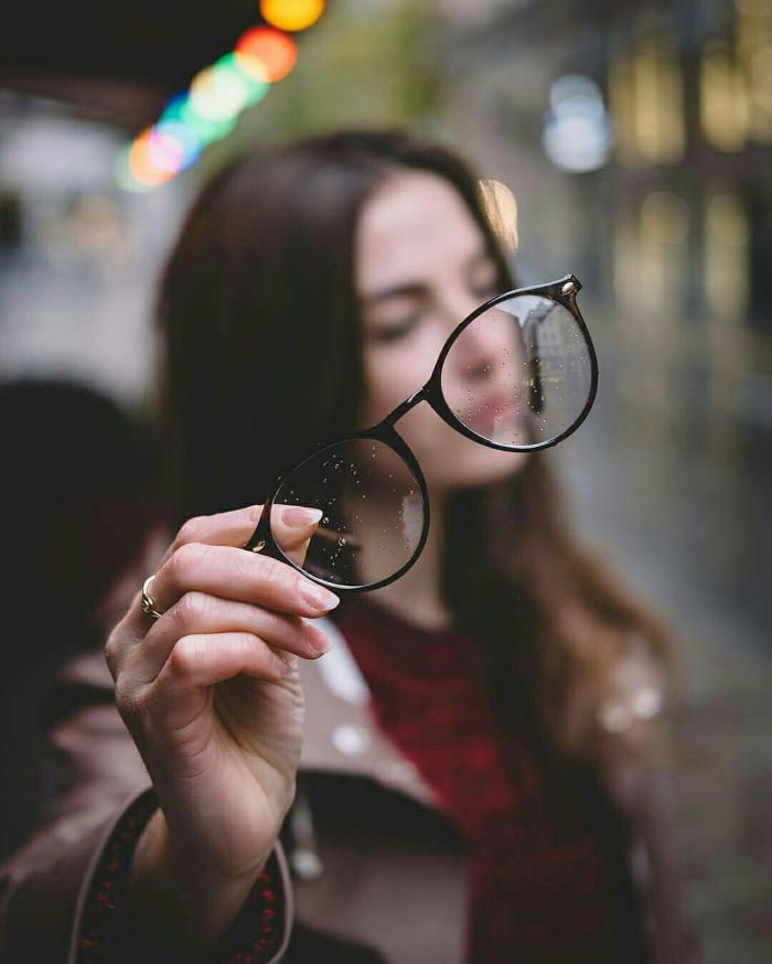 a woman holding up a pair of glasses in front of her face