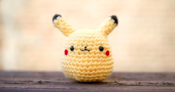 a small crocheted pikachu doll sitting on top of a wooden table