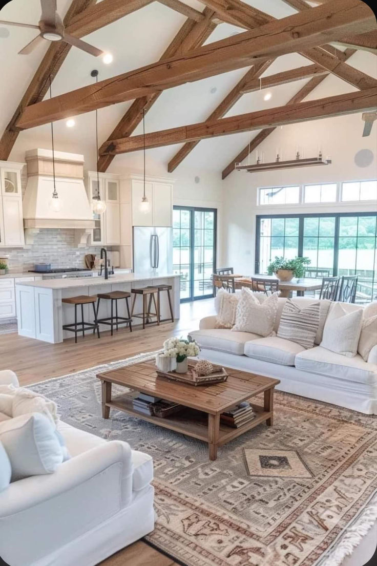 a living room filled with white furniture and wooden beams