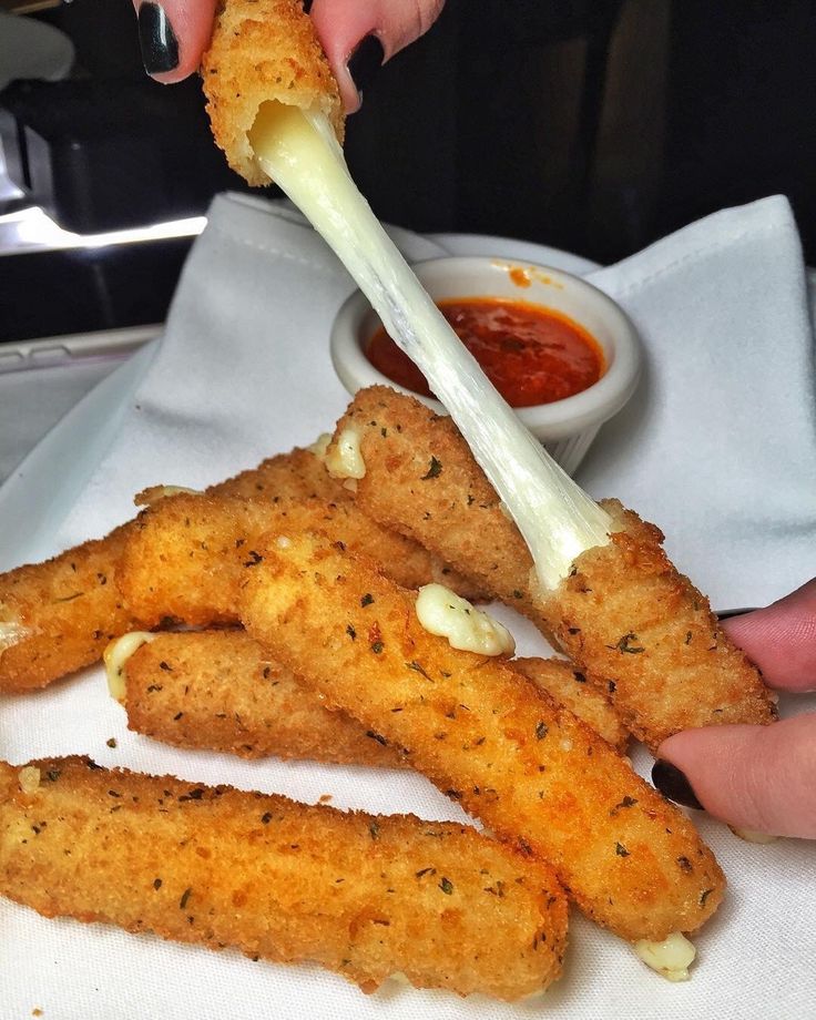 a person is dipping sauce on some fried food sticks with parmesan cheese and ketchup