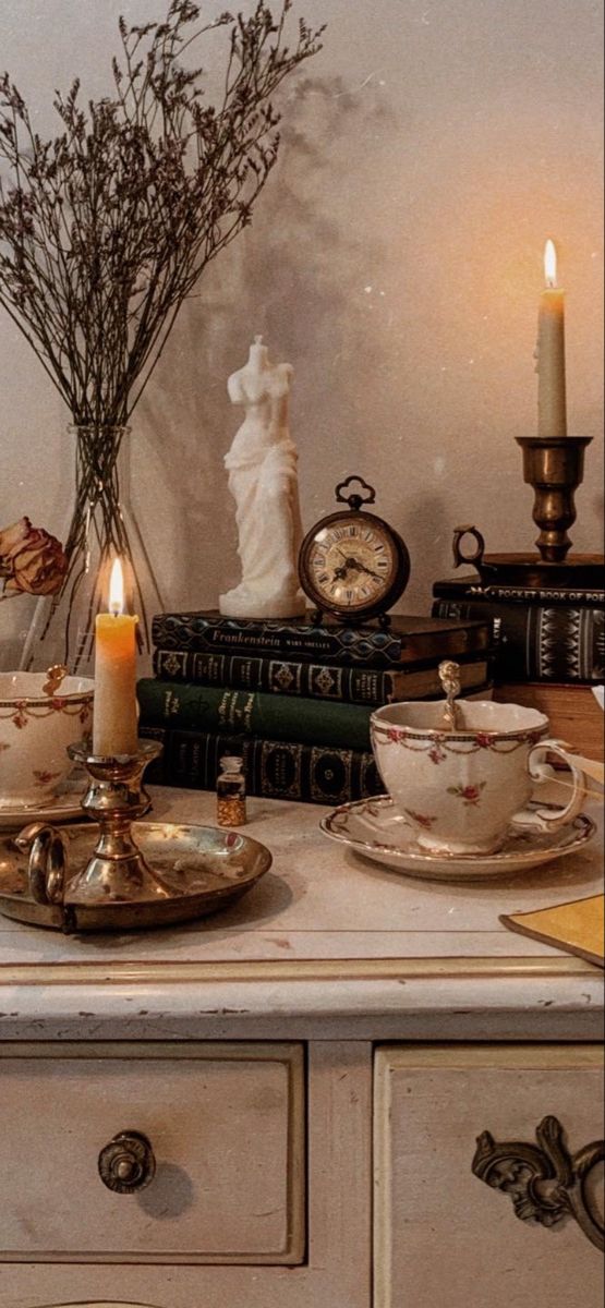 a table topped with books and candles next to a vase filled with flowers on top of it