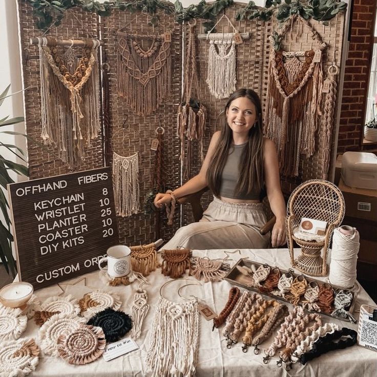 a woman sitting in front of a table filled with beads and other items for sale