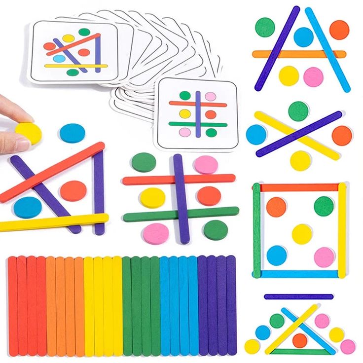 a person holding a stick next to many different shapes and sizes of pegs on a white surface