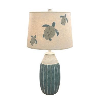 a lamp with a turtle design on the side and a light shade that is attached to it