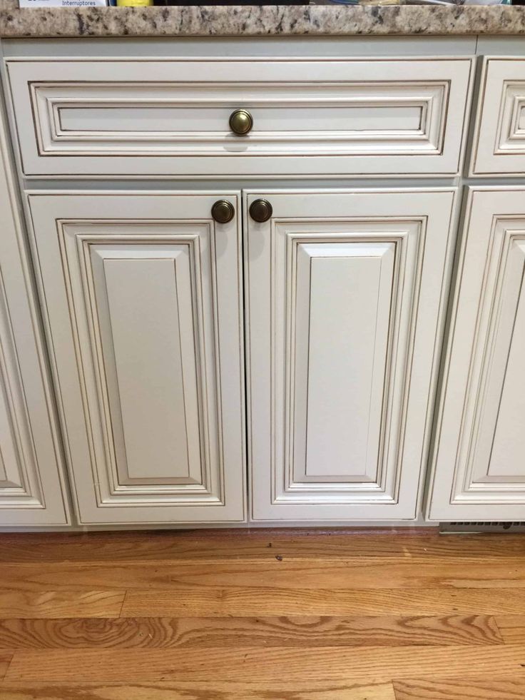 a kitchen with white cabinets and wood flooring on the side of the counter top