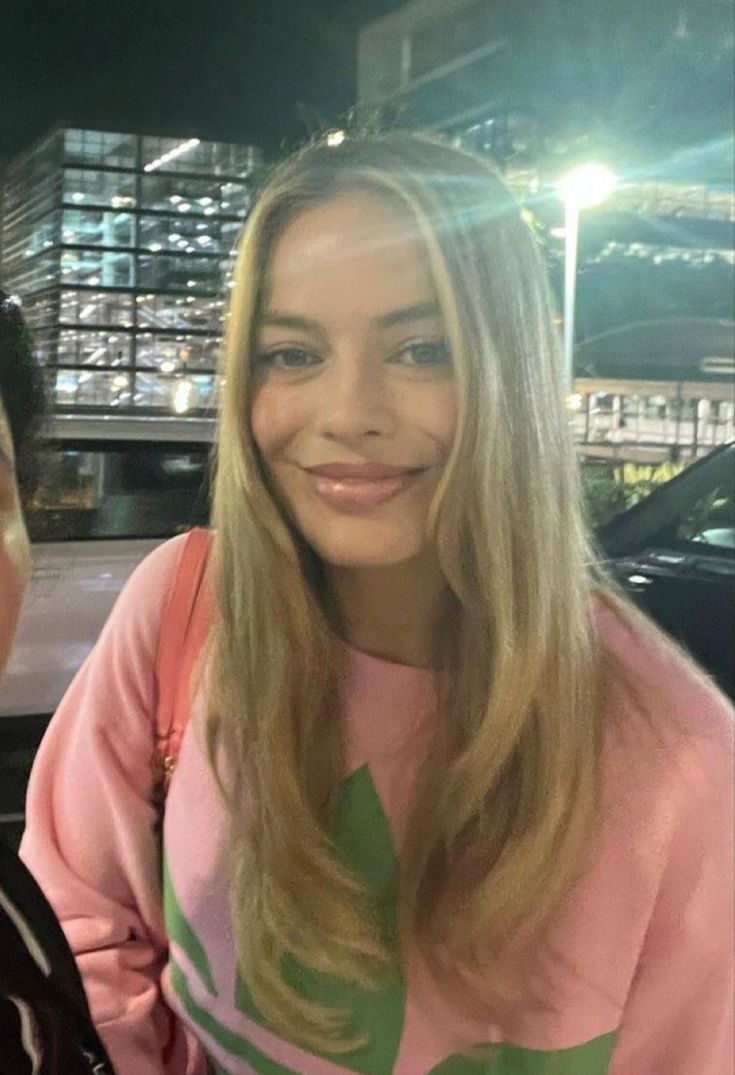 a woman with long blonde hair is smiling at the camera while sitting in a car